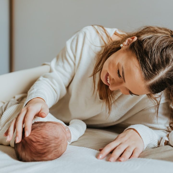Moeder speelt liefdevol met haar pasgeboren baby op een neutrale achtergrond.