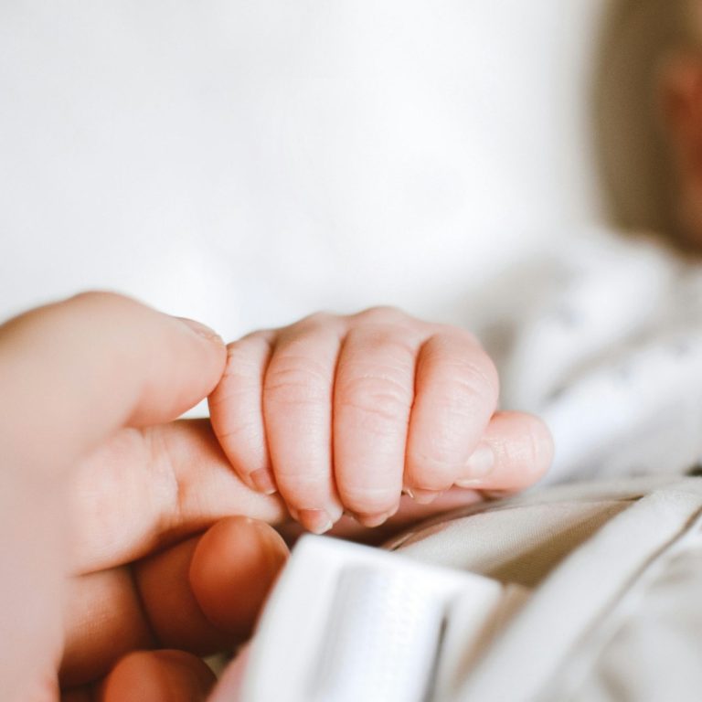 Een baby's handje dat een vinger vasthoudt.