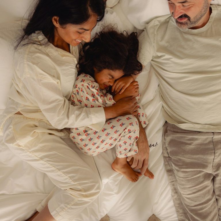 Moeder en dochter liggen in bed te knuffelen en te lachen in bed.